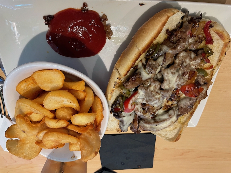 Boosters lunch featuring a Philly cheesesteak with sautéed peppers, onions, melted cheese, and sidewinder fries