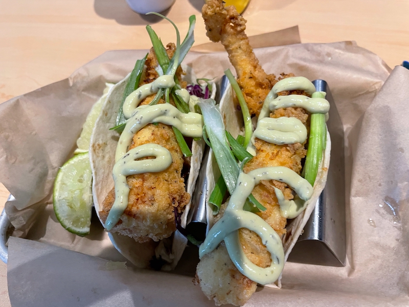 Fried fish tacos topped with slaw and avocado crema