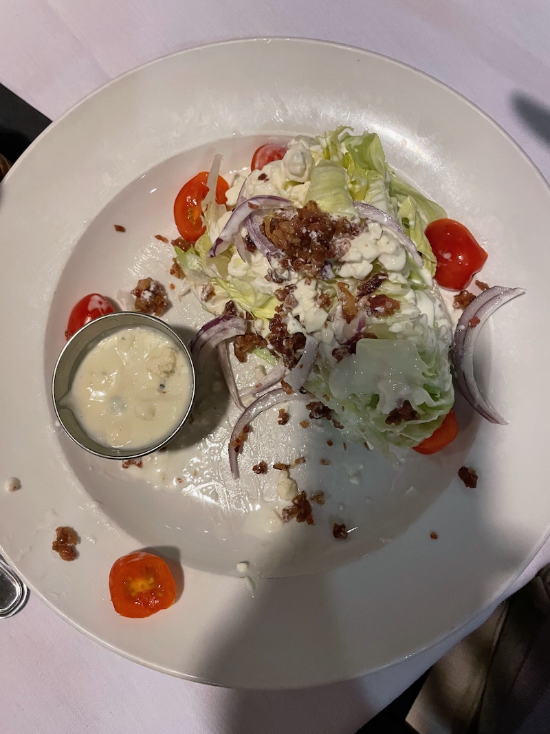 Shared wedge salad portion with dressing and bacon