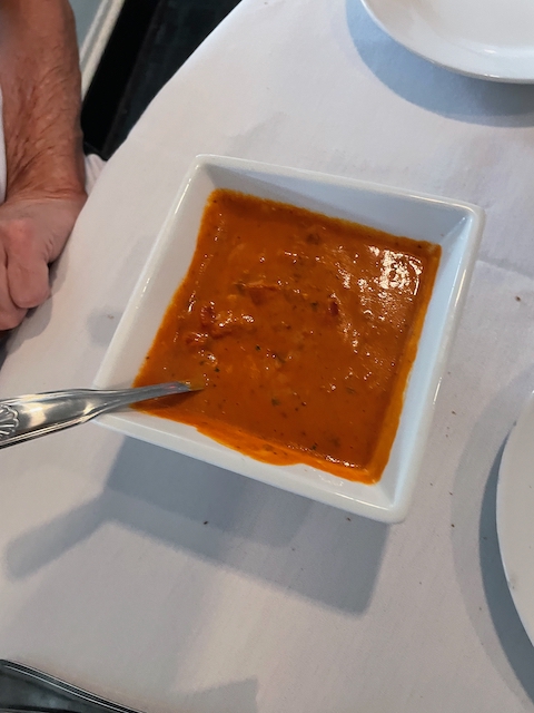 Red pepper gouda soup in a square white bowl