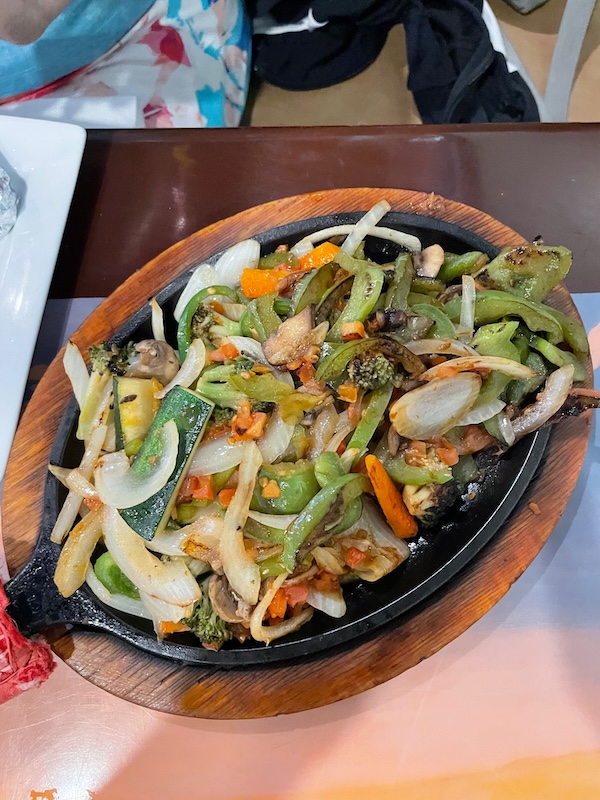 Vegetarian fajitas with peppers, onions, and mushrooms on a sizzling skillet