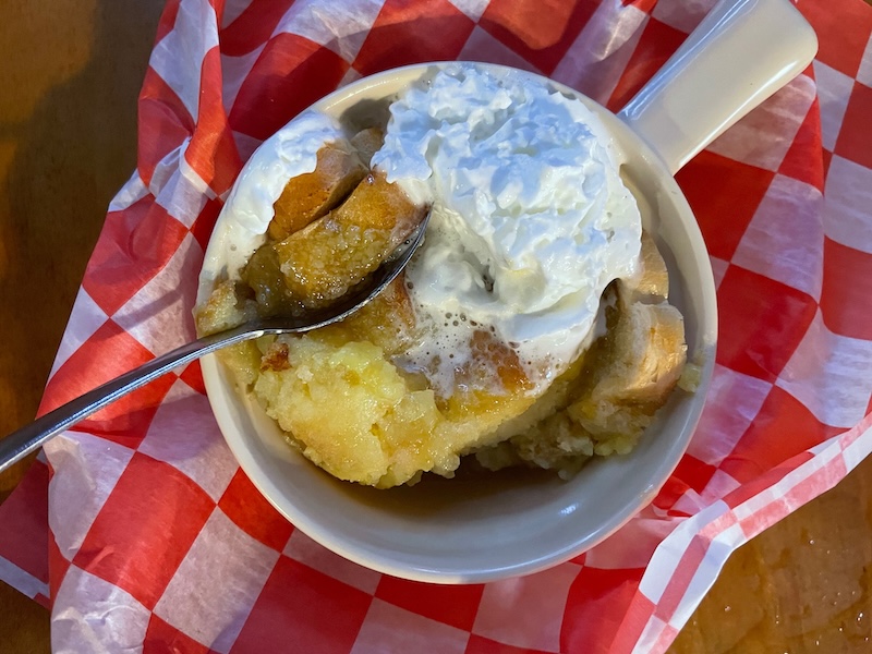 Warm bread pudding dessert topped with whipped cream