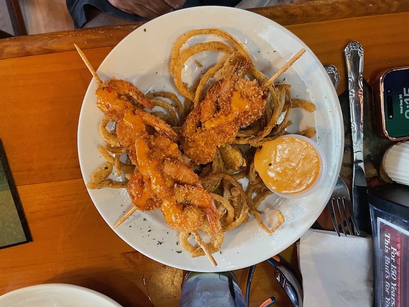 Breaded shrimp with sauce served over a pile of onion strings at R.J. Gator’s Lake Sumter Landing