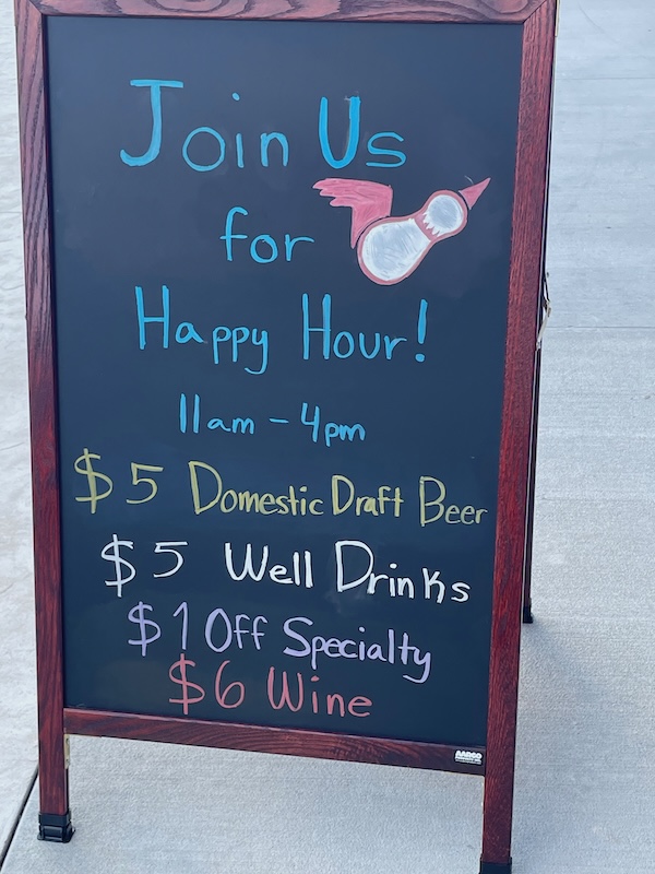 Woodrow’s happy hour sign listing drink specials from 11 a.m. to 4 p.m.